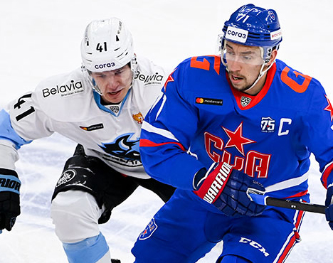 Два хоккеиста на льду в движении: игрок в синей форме с эмблемой СКА ведет шайбу, рядом - игрок в белой форме с номером 41. Видны логотипы спонсоров на форме